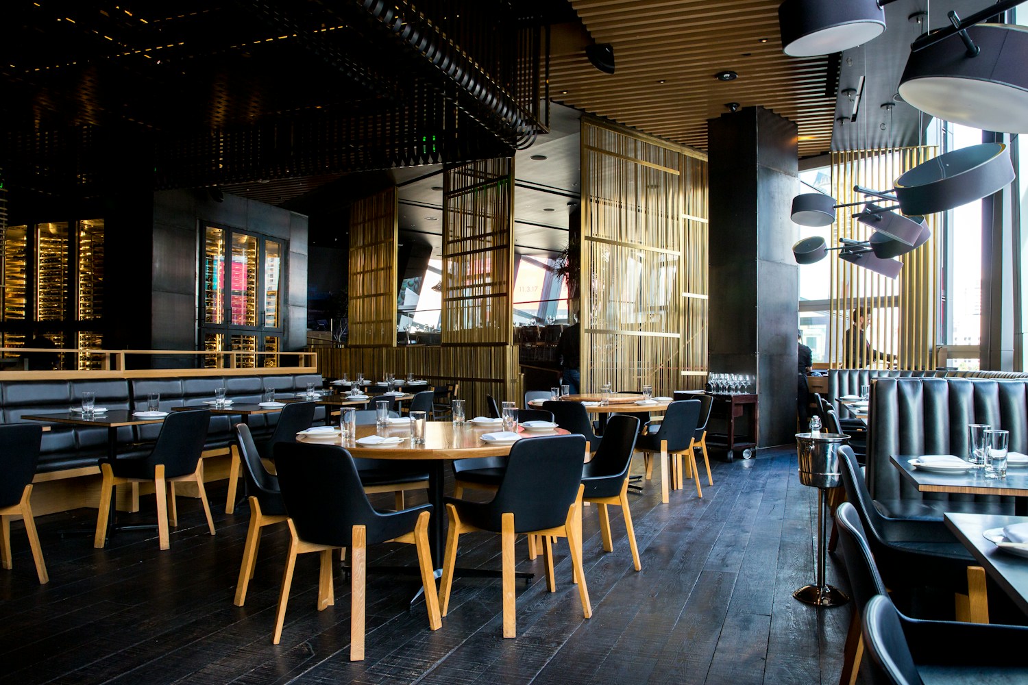 Warm, welcoming restaurant with shared tables, greenery and pendant lights